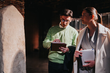 Two people engage in observation and note-taking in a museum setting, evoking themes of learning,...