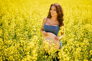 Fototapeta premium beautiful woman with a hat posing in the blooming rapeseed field on a sunny day