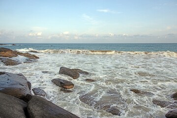 Panoramic view of a tropical beach with palm trees, rocks, and turquoise water at Goyambokka Beach near Tangalle in Sri Lanka under clear weather with gentle surf