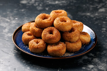 Mini cinnamon sugar donuts on blue plate