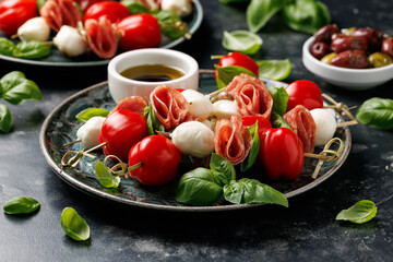 Mini skewer appetizers with salami, mozzarella and tomatoes. Healthy antipasto skewer.