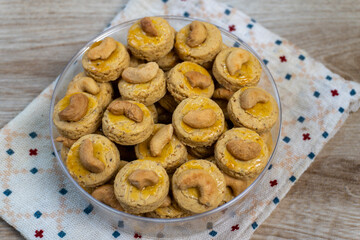 Delicious Round Cashew Cookies Topped with Cashew Nuts, Arranged in a Clear Bowl on a White and Blue Patterned Napkin, Perfect for Eid Al-Fitr Celebrations
