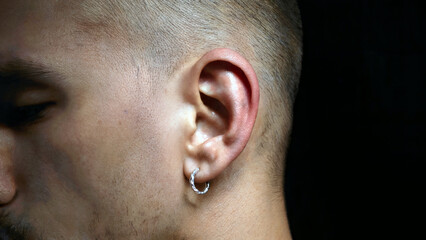 Obraz premium Mans Ear with Silver Piercing in Dark High Contrast Lighting