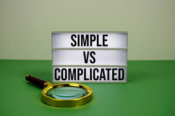 Simple vs Complicated text on light box on green background