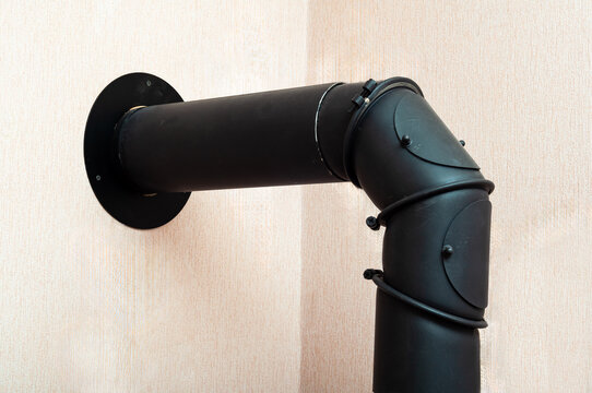 A black flue pipe makes a ninety degree turn near the wall for venting a wood stove.