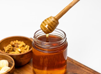 Close up shot of honey dripping from honey dipper in a jar of honey