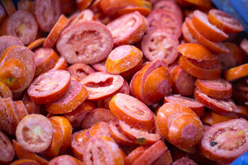 Close-up of shock-frozen sliced red tomatoes with a thin ice coating. Are prepared for retail packaging to ensure extended shelf life in supermarkets and maintain perishable harvest quality.