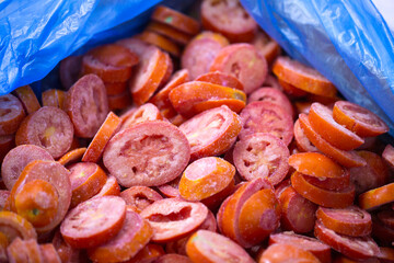 Close-up of shock-frozen sliced red tomatoes with a thin ice coating. Are prepared for retail packaging to ensure extended shelf life in supermarkets and maintain perishable harvest quality.