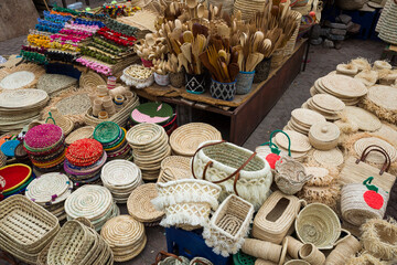 Traditional Moroccan market stall in the old town of Marrakech, Morocco, displaying handmade woven baskets, straw goods, colorful textiles, and wooden utensils