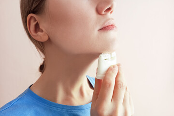 Young caucasian woman with massager near her face. Facial massage. Pink background.