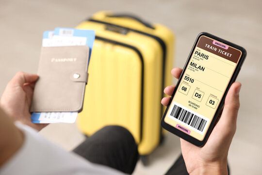 Tourist holding mobile phone with e-ticket for train and passport indoors, closeup