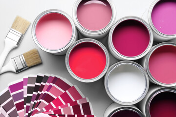 Cans with paint in different shades, brushes and color palette on white background, top view