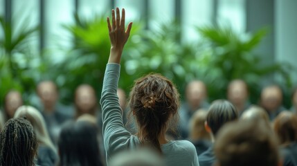 Person raising hand in a crowd of people with plants in background.