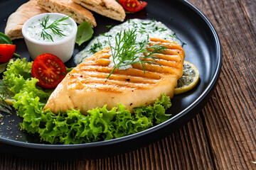 Grilled chicken breast, pita bread and tzatziki sauce on wooden table. Greek style food
