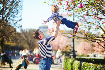 Fototapeta premium Beautiful young mother and her adorable toddler daughter walking together in park in Paris, France.