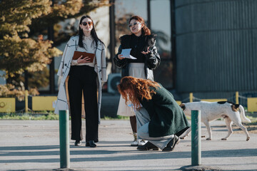 Three individuals gathered outdoors near buildings on a bright day, discussing and engaging in activities