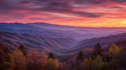 Obraz premium Colorful sunset over smoky mountain range with glowing clouds and layered forest landscape