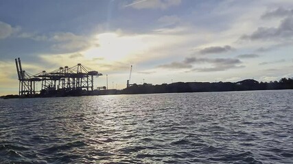 Video of ship to shore container cranes or ship to shore gantry crane in port under a cloudy sunset