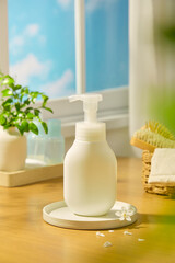 Frontal shot of pump bottle mockup, sitting on a circular stone podium with daisy petals scattered around. Behind are micellar water bottles and indoor plants, placed near the windowsill.