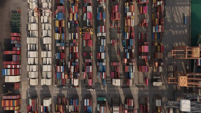 VDO 4KAerial top view over international containers cargo ship at industrial import-export port prepare to load containers with big container loader ship vessel. global transportation and logistic bus