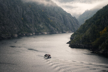 A boat takes a tourist tour between the granite cliffs of the Sil River