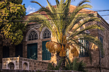  Traditional Lebanese house at recreation town by the sea Batroun. Stone house with wooden windows and palm tree garden, Lebanon