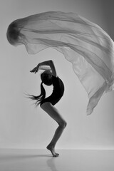 A girl in a swimsuit and a dress shows beautiful athletic elements on a white background. Ballet, rhythmic gymnastics, fabric, aesthetics, grace