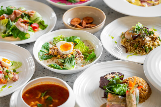 A selection of gourmet dishes elegantly plated, featuring fresh ingredients like eggs, greens, meats, and vegetables, creating a vibrant and appetizing meal presentation.