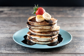 Pancakes with chocolate and fruit on wooden table