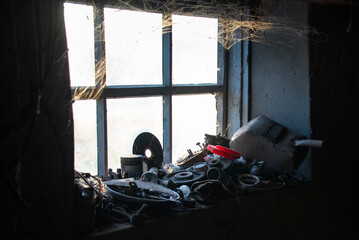 Auto mechanic's workshop. Light in the window, age-old cobwebs. Tools on the windowsill. Necessary items in the everyday life of an auto mechanic.