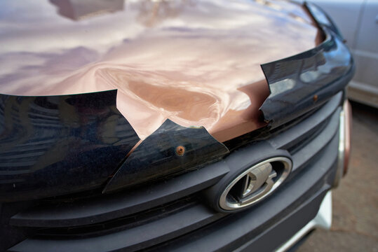 Minsk, Belarus. Mar 16, 2025. Lada car with cracked bonnet deflector and damaged hood, aftermath of minor collision with visible damage to a car's front end. Broken bug shield and visible hood damage