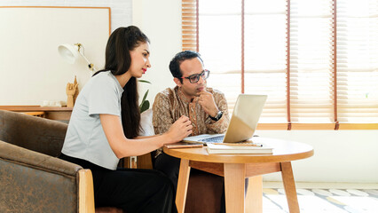 Two small business professionals working together at a cozy home office, reviewing data on a laptop. Perfect image for remote teamwork, business consulting, planning, and financial collaboration.