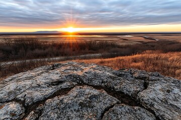 Stunning Sunset View from Rocky Hilltop Overlooking Serene Prairie Landscape