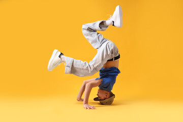Boy in stylish clothes dancing on orange background