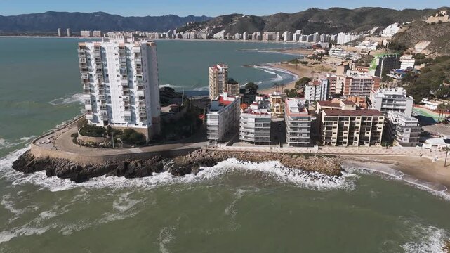 High-altitude pan of city near Platja de l'Illa and surrounding urban beachscape