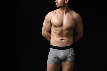 Young man in stylish light grey underwear on black background, closeup