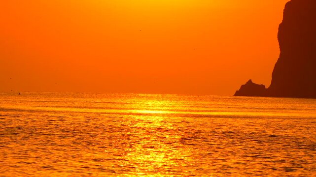 Sunset, Ocean, Cliffs - A stunning sunset over the ocean with silhouetted cliffs in the distance.