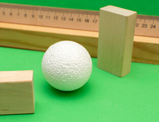 Still life with wooden blocks and a a plastic foam ball on green background	