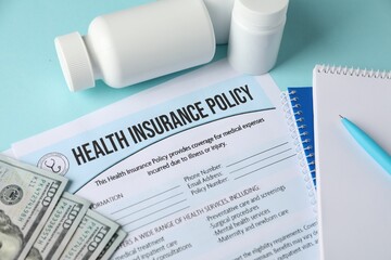 Health insurance policy, money and medical bottles on turquoise background, above view