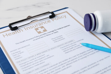 Health insurance policy, pen and medical bottle on white marble table, closeup