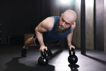 Sportsman doing kettlebell push up during workout in gym