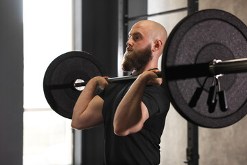 Sportsman with barbell during workout in gym