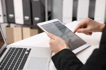 Electronic signature. Man using tablet at white table, closeup