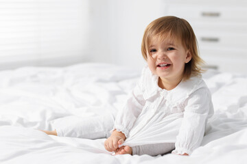 Naklejka premium Cute little baby girl on bed at home. Space for text