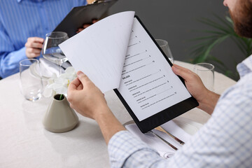 Couple choosing dishes from menu at table in restaurant, closeup