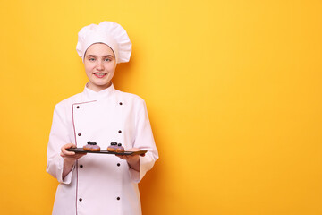 Confectioner in uniform holding delicious eclairs on orange background, space for text
