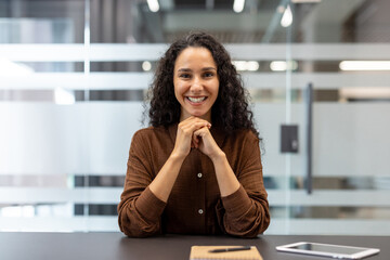 Webcam view, online video presentation seminar meeting, young successful woman looking at camera while sitting at desk inside office. Conference with partners and clients businesswoman smiling.