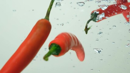 Hot chili peppers submerging in water slow motion close-up. - Powered by Adobe
