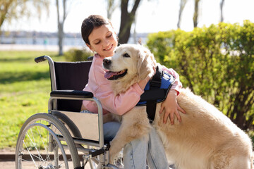 Girl in wheelchair hugging her service dog at park