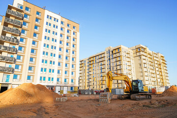 Excavator on earthworks on Construction site. Building under construction. Excavator on groundwork. Backhoe on earthmoving. Earthmover. Buildings construction and renovation..